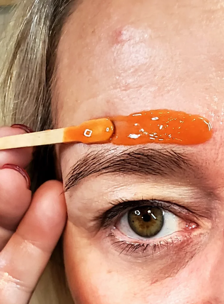 Augenbrauen Waxing, Wachs wird oberhalb der Augenbraue aufgetragen.