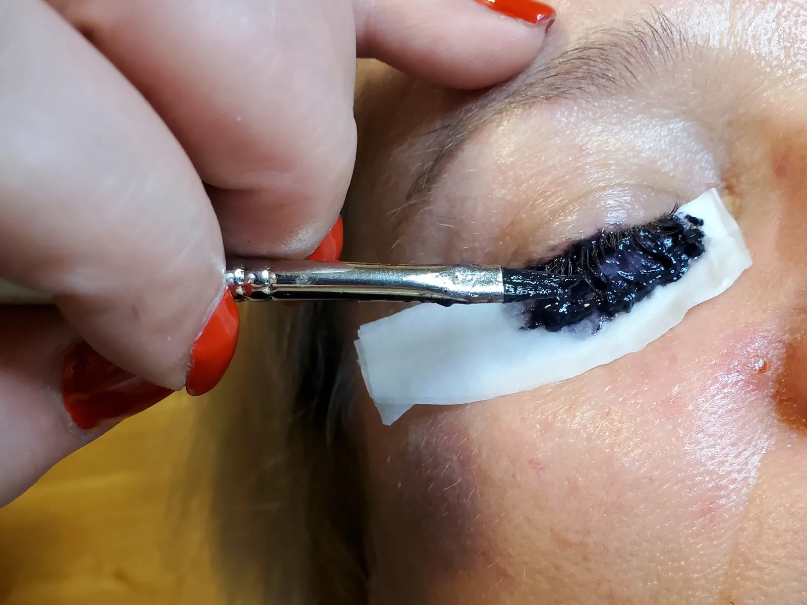 Wimpern f&auml;rben, Farbe wird mit Pinsel aufgetragen, Schutzpad unter dem Auge.